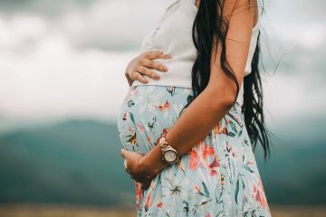 Беременная женщина держит руки на животе